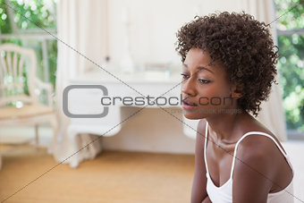 Thoughtful woman sitting on bed