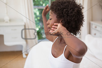 Pretty woman sitting on bed yawning
