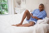 Happy man sitting on bed sending text