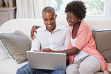 Happy couple relaxing on the couch with laptop