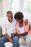 Happy couple relaxing on the couch with smartphone