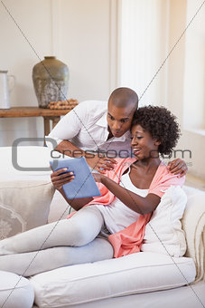 Happy couple relaxing together on the couch using tablet