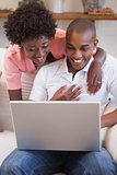 Happy couple relaxing together on the couch using laptop