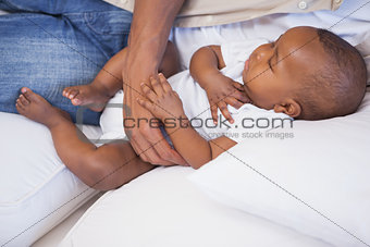 Happy father napping with baby son on couch