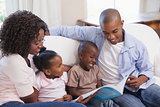 Happy family sitting on couch together reading book