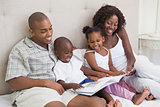 Happy family lying on bed reading book