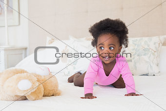 Baby girl in pink babygro crawling on bed