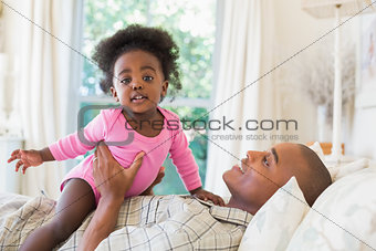 Father and baby girl lying on bed together