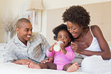 Happy parents with baby girl on their bed