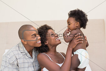 Happy couple on bed with baby daughter