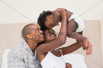 Happy couple on bed with baby daughter