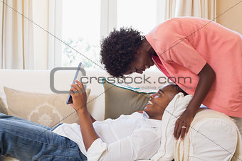 Cute couple relaxing on couch with tablet pc