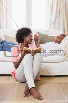 Cute couple relaxing reading book and using smartphone