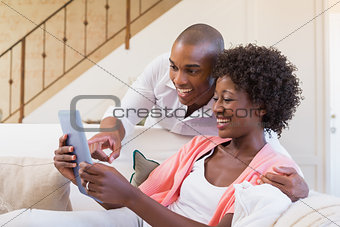 Cute couple relaxing on couch with tablet pc