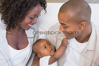 Happy young parents spending time with baby on the couch
