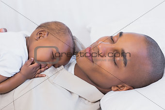 Happy young father napping with baby son on couch