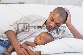 Happy young father with baby son on couch