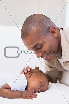 Adorable baby boy sleeping while being watched by father
