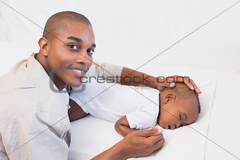 Adorable baby boy sleeping while being watched by father