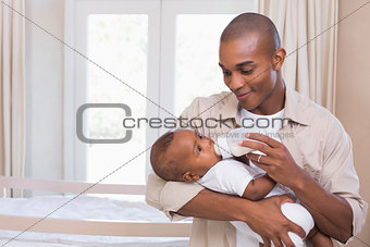 Happy father feeding his baby boy a bottle
