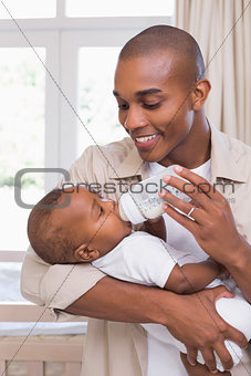 Happy father feeding his baby boy a bottle