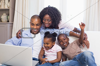 Happy family on the couch together using laptop