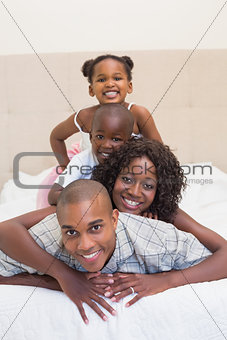 Happy family smiling at camera together on bed