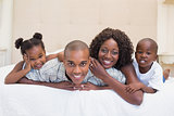 Happy family smiling at camera together on bed