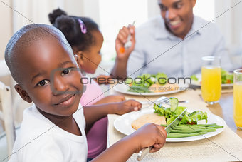 Family enjoying a healthy meal together with son smiling at camera