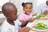 Family enjoying a healthy meal together with daughter smiling at camera