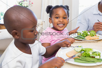 Family enjoying a healthy meal together with daughter smiling at camera
