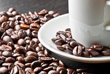 white cup with coffee near coffee beans