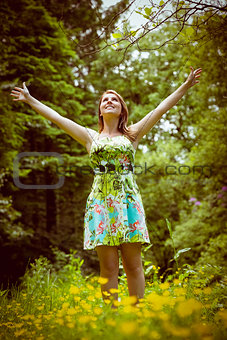 Woman with arms outstretched in field against trees