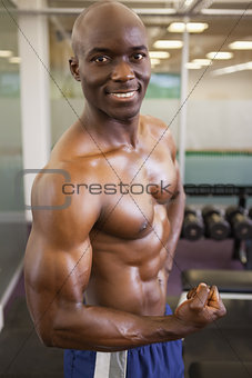 Smiling shirtless muscular man posing in gym