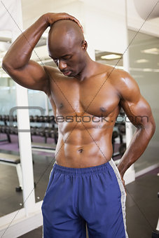 Serious shirtless muscular man posing in gym