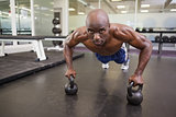 Muscular man doing push ups in gym