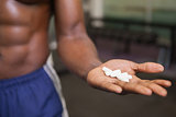 Muscular man holding vitamin pills in hand