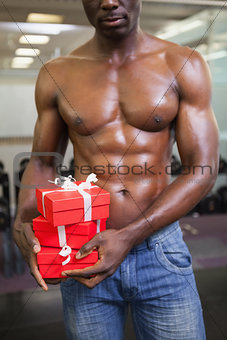 Mid section of a muscular man with gift boxes