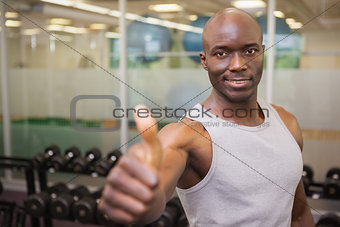 Muscular man giving thumbs up in gym
