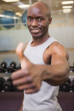 Muscular man giving thumbs up in gym