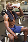 Muscular man drinking protein in gym