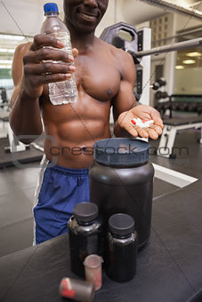 Shirtless muscular man holding vitamin pills