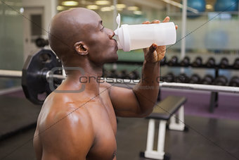 Sporty young man drinking protein in gym