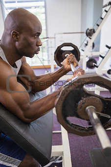 Determined muscular man lifting barbell in gym