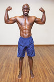 Shirtless muscular man flexing muscles in gym