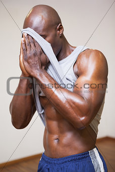 Muscular man wiping sweat after workout