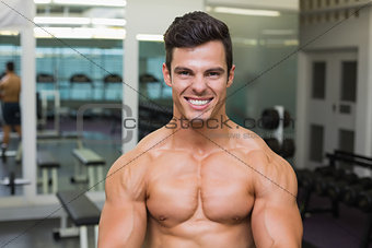 Smiling shirtless muscular man in gym