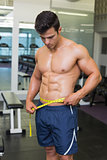 Shirtless muscular man measuring waist