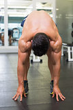 Shirtless muscular man bending in gym