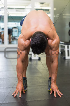 Shirtless muscular man bending in gym